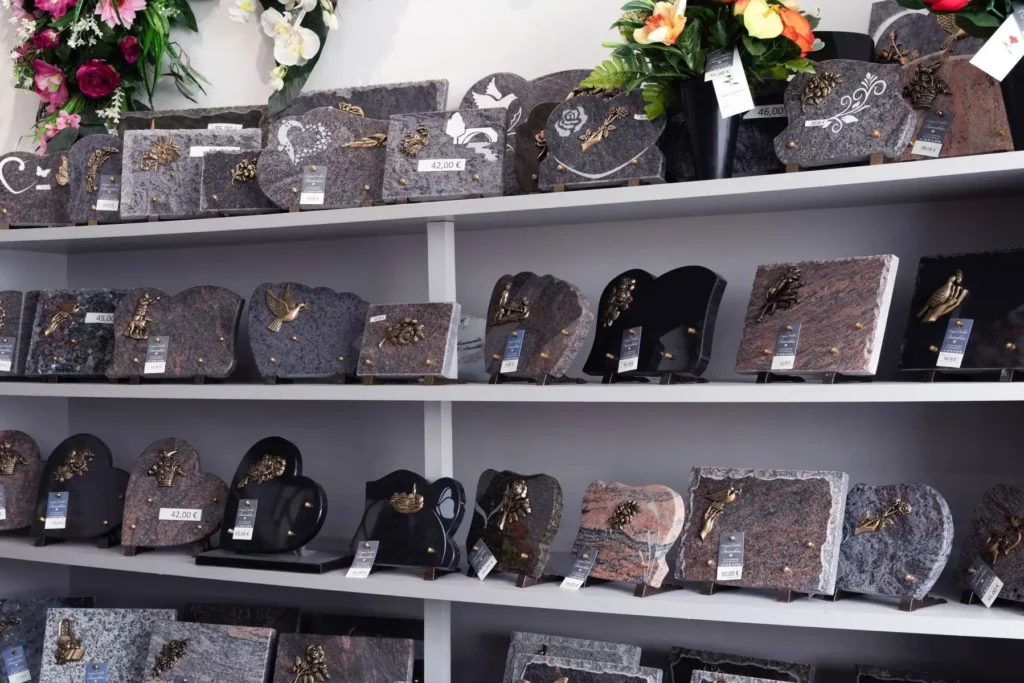 Exposition de plaques funéraires en granit gravées sur des étagères d'agence.